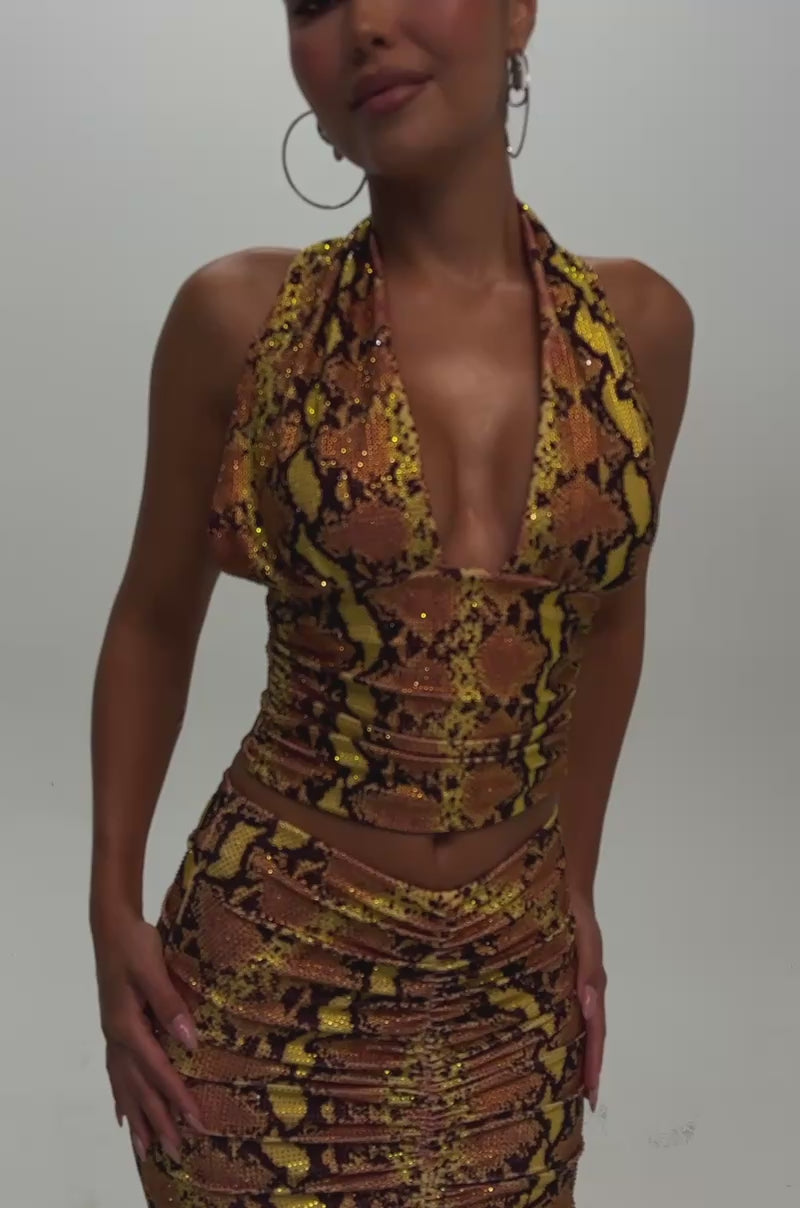 Video of a woman modeling the HUNTER RHINESTONE TOP—a sleeveless, deep V-neck yellow snake print halter.