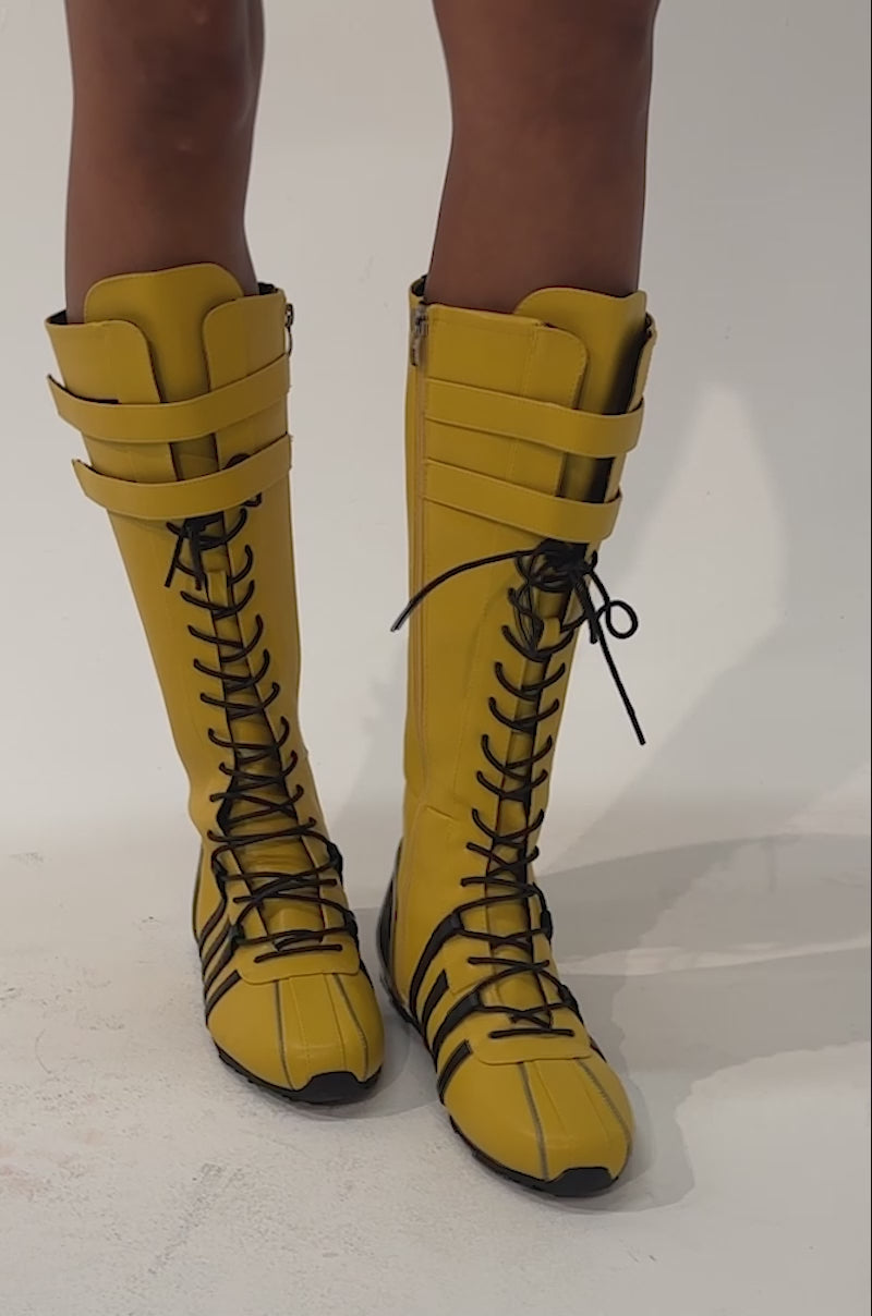 Video of a woman modeling the AZALEA WANG OZZY YELLOW KNEE HIGH SNEAKER featuring bold yellow faux leather with black stripes and accents.