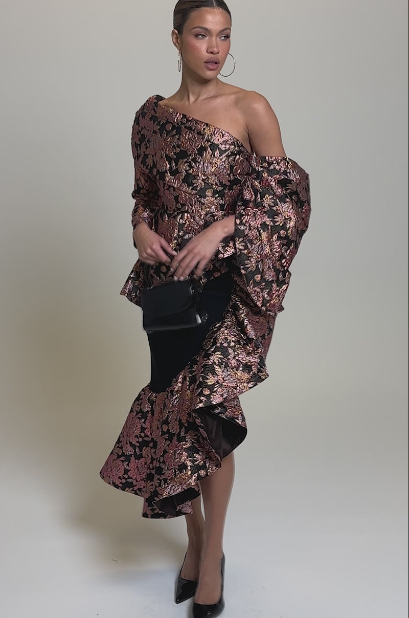 Video of woman modeling the SO MUCH IN LOVE BROCADE BLOUSE, featuring bold metallic pink floral patterns on black, paired with hoop earrings and her hair styled back.