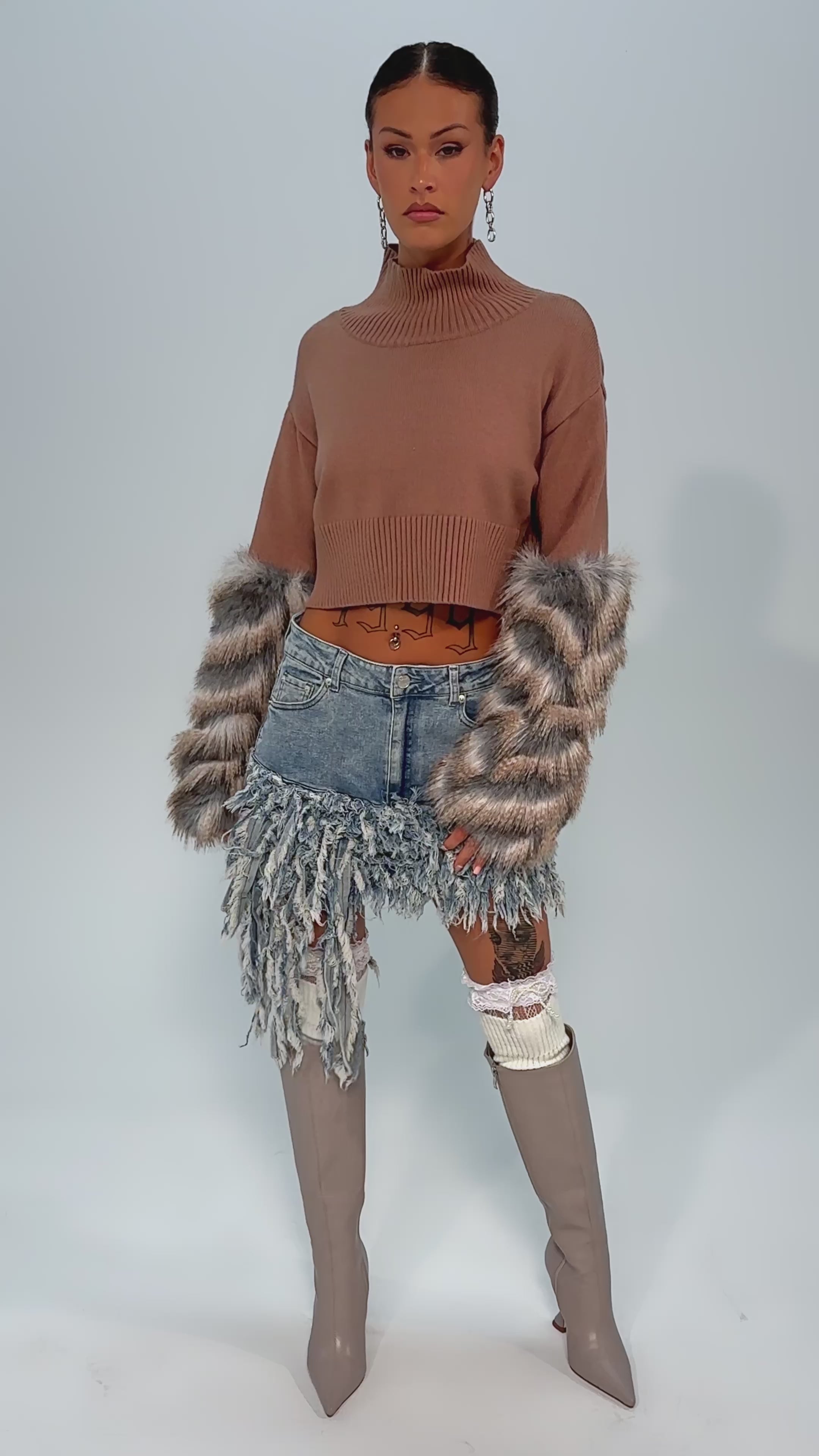 Video of woman modeling the OPEN UP YOUR LOVE DENIM SKIRT—a distressed mini skirt with frayed denim strips—beige knee-high boots, and white thigh-high socks with lace accents.