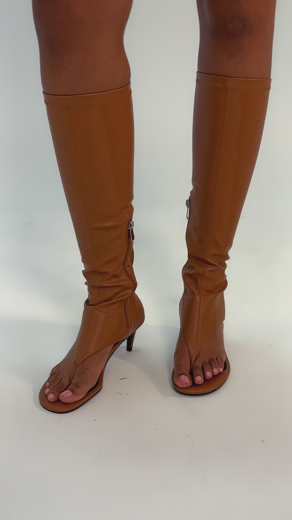 Video of woman modeling the AZALEA WANG CECILE TAN PU SANDAL—tan, open-toe, knee-high heeled boots with a stiletto heel and side zipper—stands on a light background. Only their legs and feet are visible.