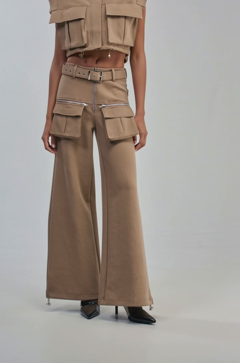 Video of a woman modeling the THAT GIRL SCUBA CARGO PANT IN TAUPE—high-waisted with a wide-leg silhouette, large cargo pockets, zippers, and a matching belt.