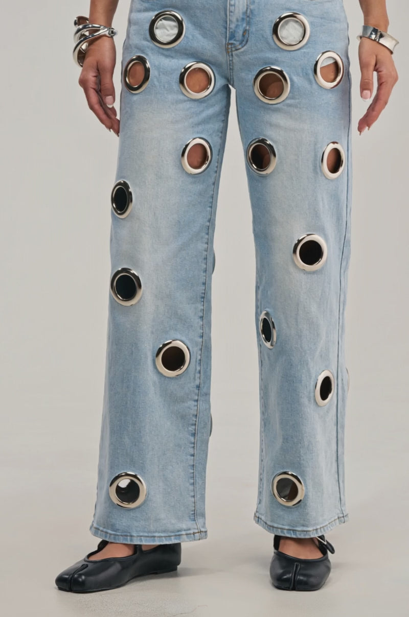 Video of a woman modeling the COOL GIRL ALERT DENIM WITH GROMMETS—wide-leg jeans featuring large holes and grommet details.