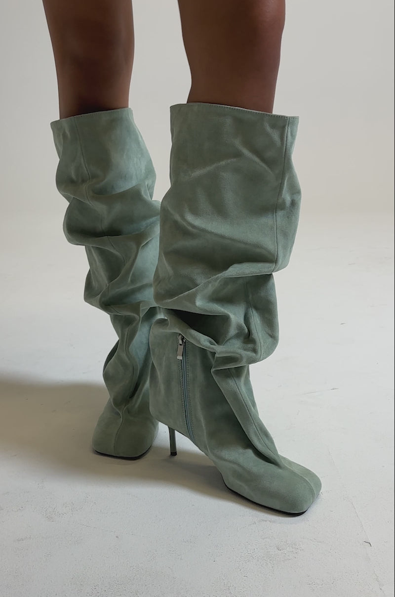 A video of someone wearing the AZALEA WANG RANDALL SAGE FAUX SUEDE STILETTO BOOT—light green, ruched, slouchy boots with thin high heels—standing on a neutral background.