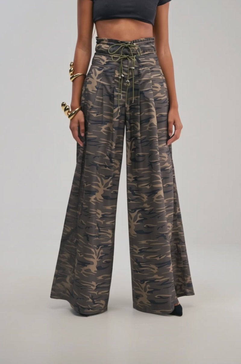 Video of a woman modeling the “DANCE THE NIGHT AWAY CAMO PALAZZO PANT,” pairing these wide-leg camouflage pants with a black crop top and high-waisted streetwear. 