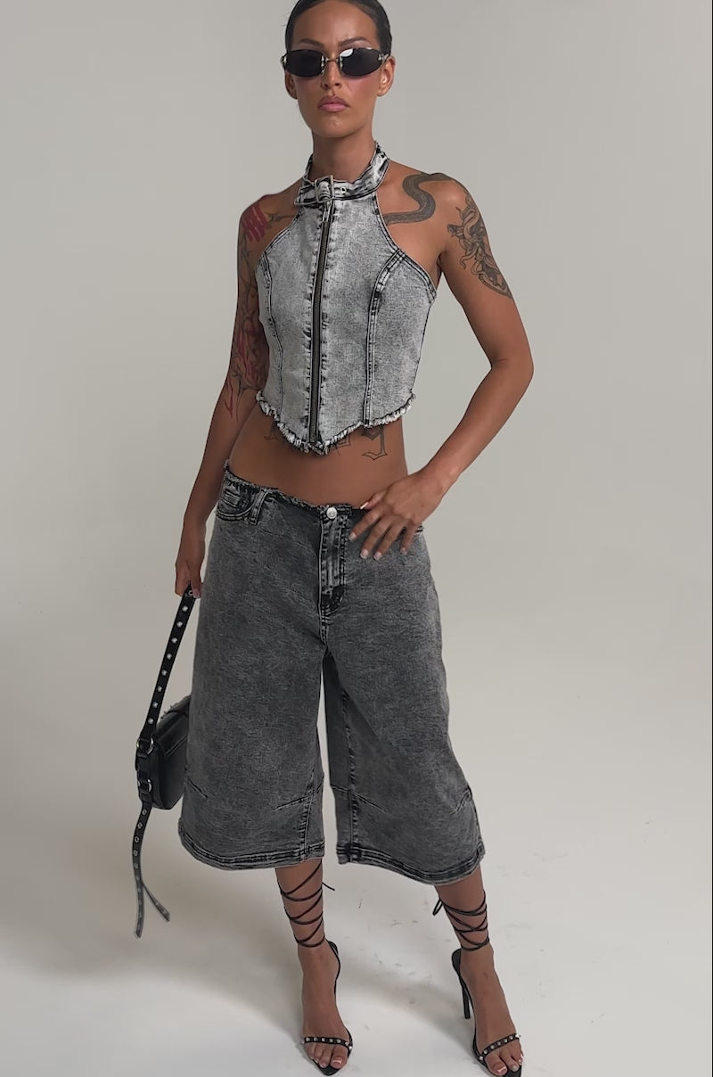 Video of woman modeling the BREAK UP WITH HIM DENIM TOP—a washed grey halter with a front zipper and frayed hem—paired with matching low-rise jeans, her tattoos adding edge to this streetwear look