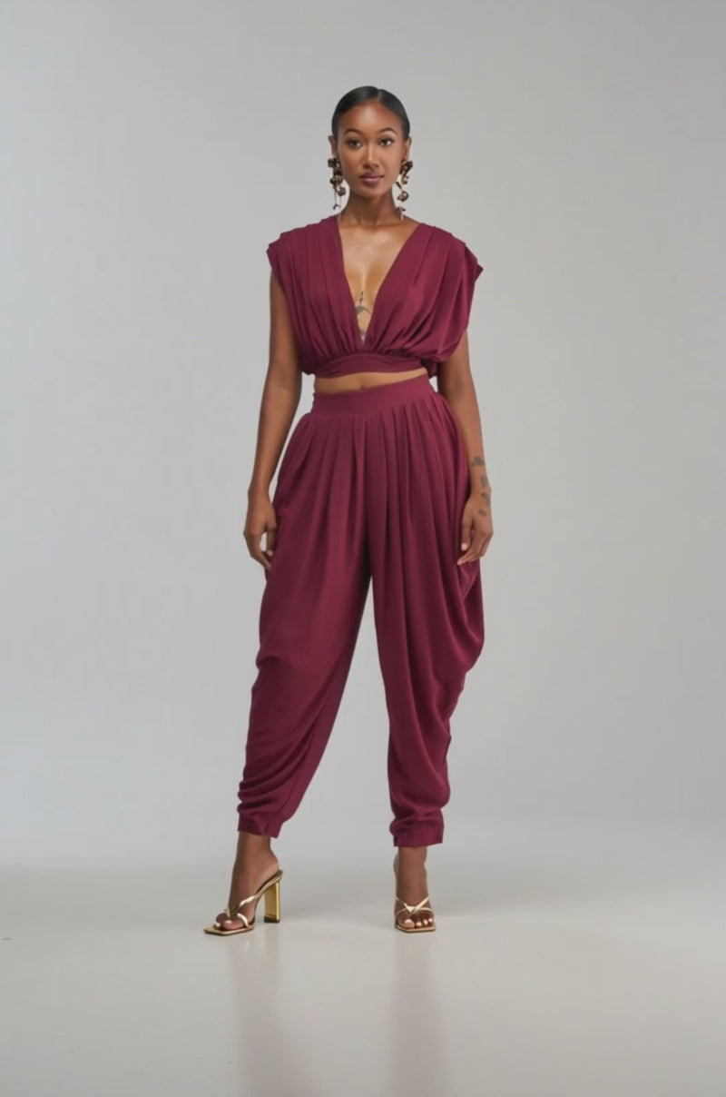 Video of a woman modeling the READY TO DANCE SLINKY BLOUSE IN BURGUNDY—a sleeveless, deep V-neck cropped top.