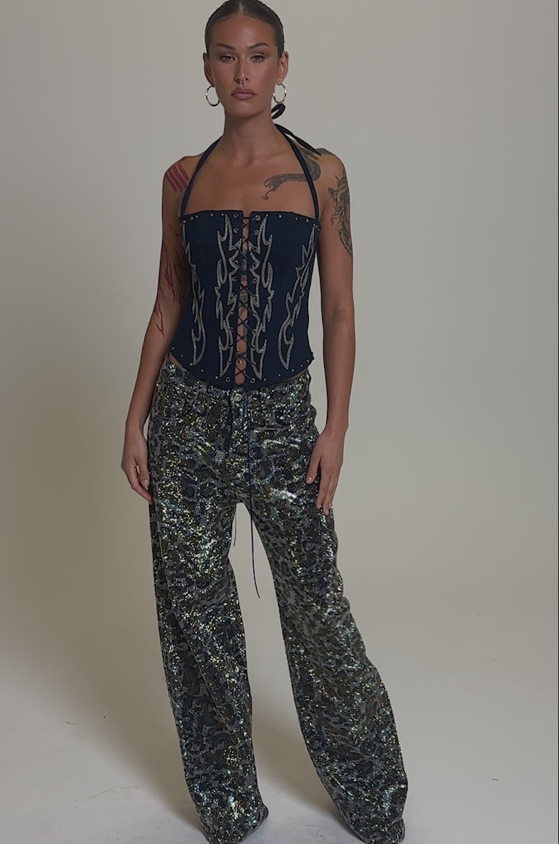 Video of woman modeling the CHEETAH GIRLY RHINESTONE DENIM PANT—high-waisted, wide-leg jeans featuring a metallic leopard print—stands with one hand at their side