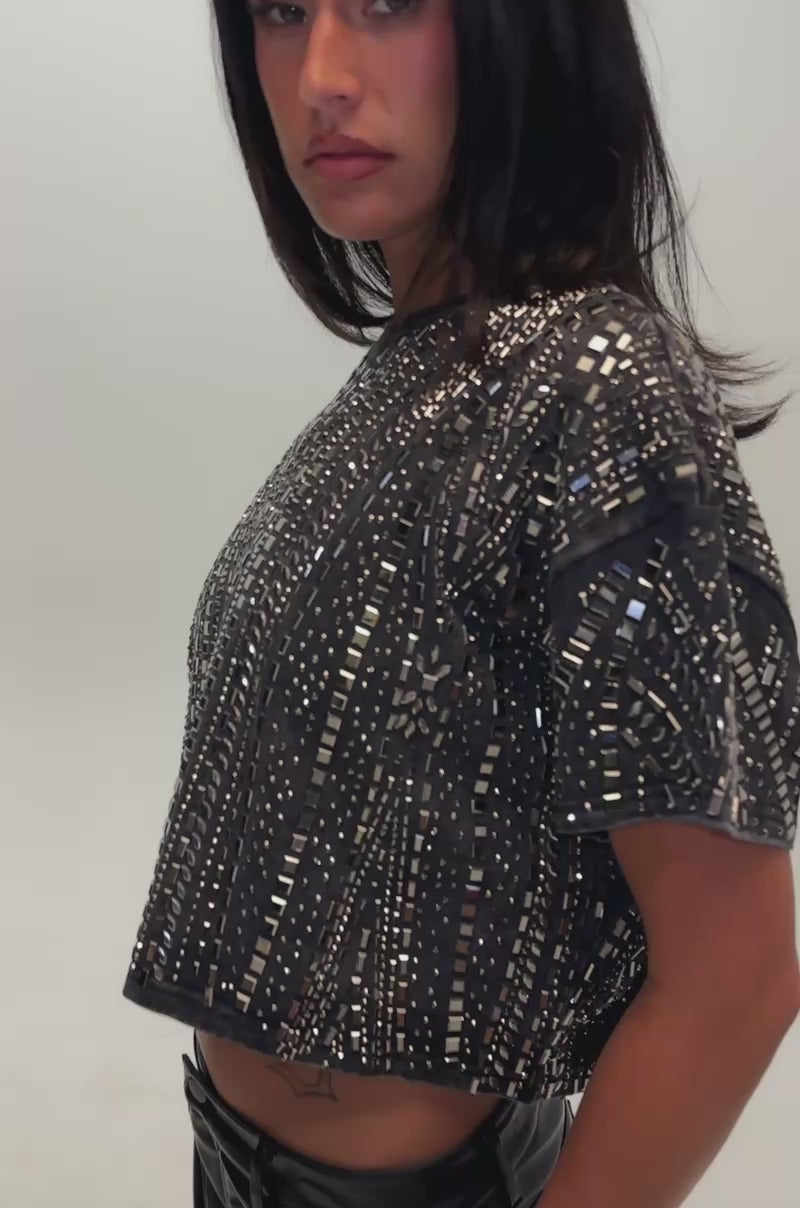 Video of a woman modeling the OVER THE TOP RHINESTONE TEE in charcoal—a cropped fit, studded geometric-patterned top.
