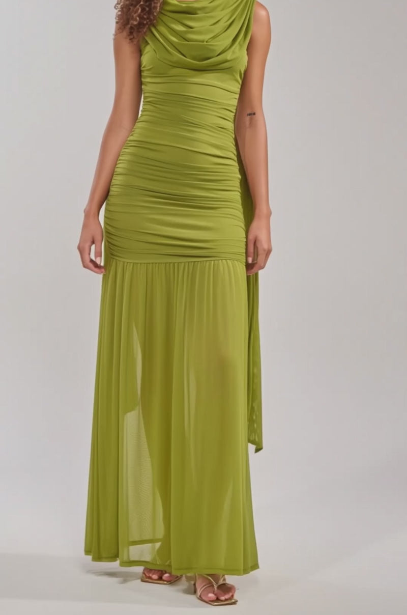 Video of woman modeling the TRENDSETTER ENERGY Layered Maxi Dress in green—sleeveless with ruched details, a sheer skirt, and a matching scarf—paired with gold heels against a plain background.