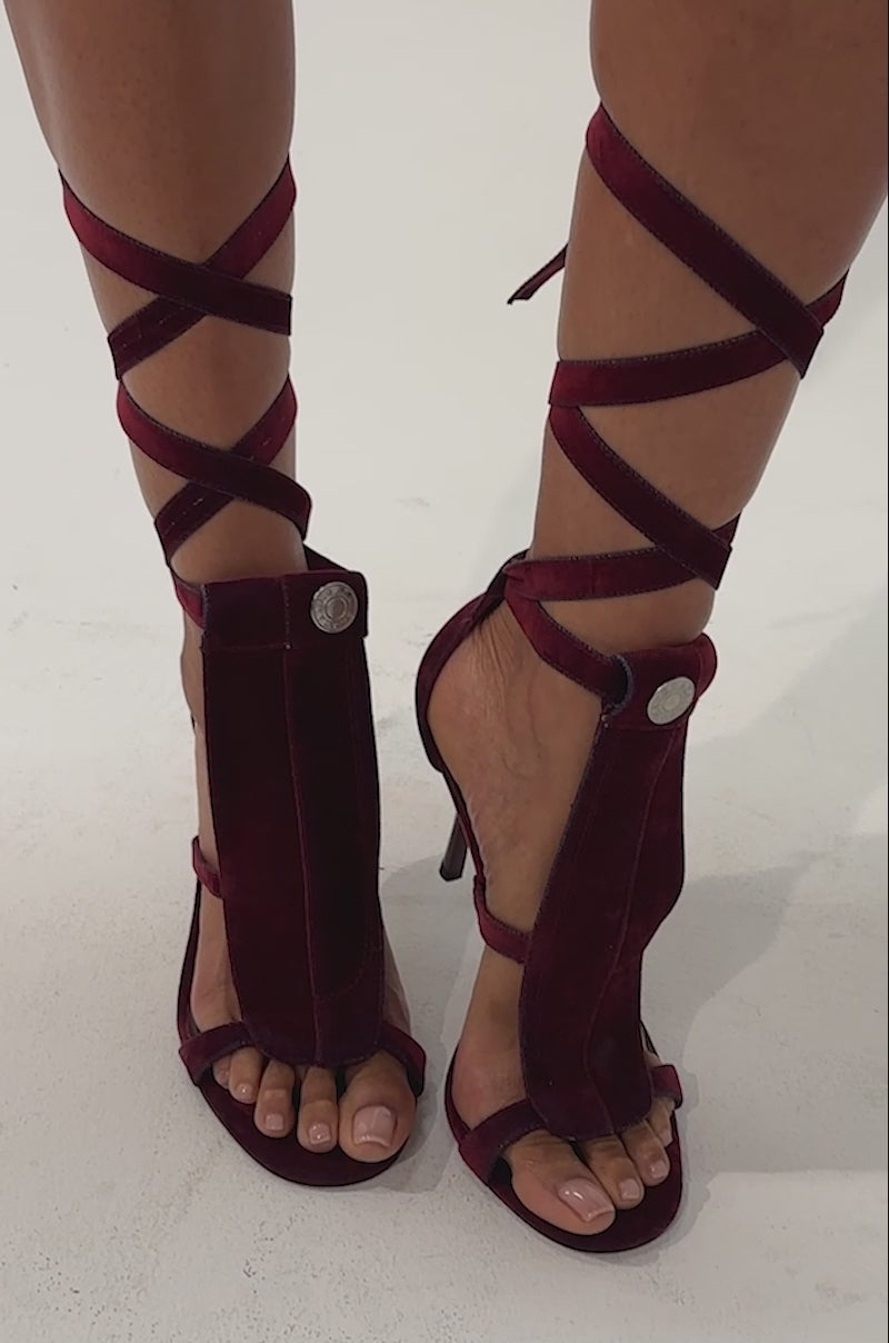 Video of a woman modeling the AKIRA GOLD NORMAJEAN Burgundy Denim Washed Sandal—high-heeled, open-toe stiletto sandals with lace-up straps wrapping around their lower legs.