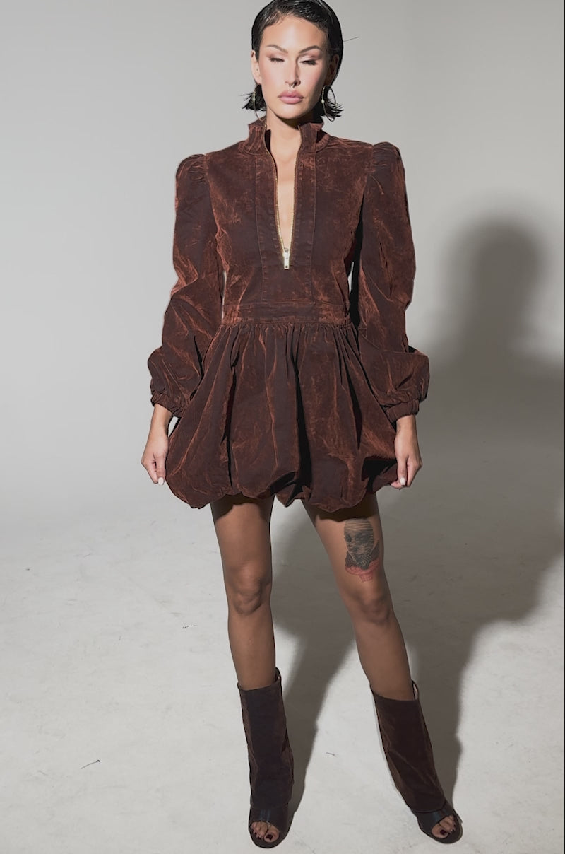 Video of woman modeling the PASS THE BUBBLY MINI DRESS IN VELVET DENIM, featuring puff sleeves, a bubble hem, front zipper, and voluminous skirt. 