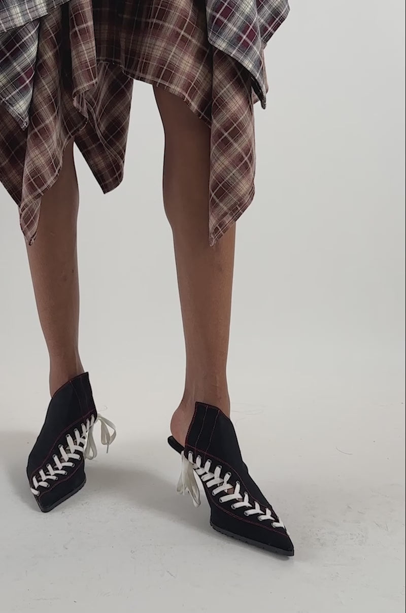 Video of a woman modeling the AZALEA WANG STRIKE OUT SPORTY STILETTO MULE PUMP—sleek black pointed-toe heels with white sneaker-inspired laces.