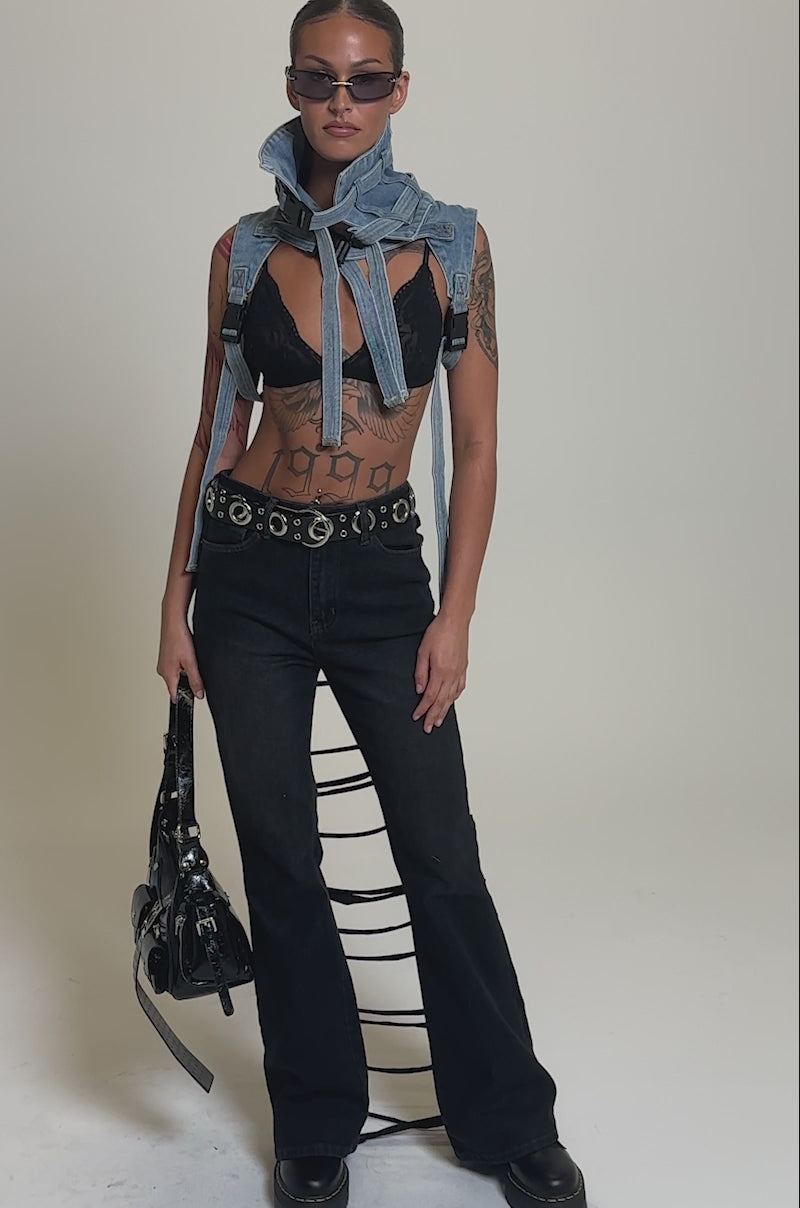 Video of woman modeling the TRY ME FLARE DENIM, this person holds a black studded handbag and shows torso tattoos. 