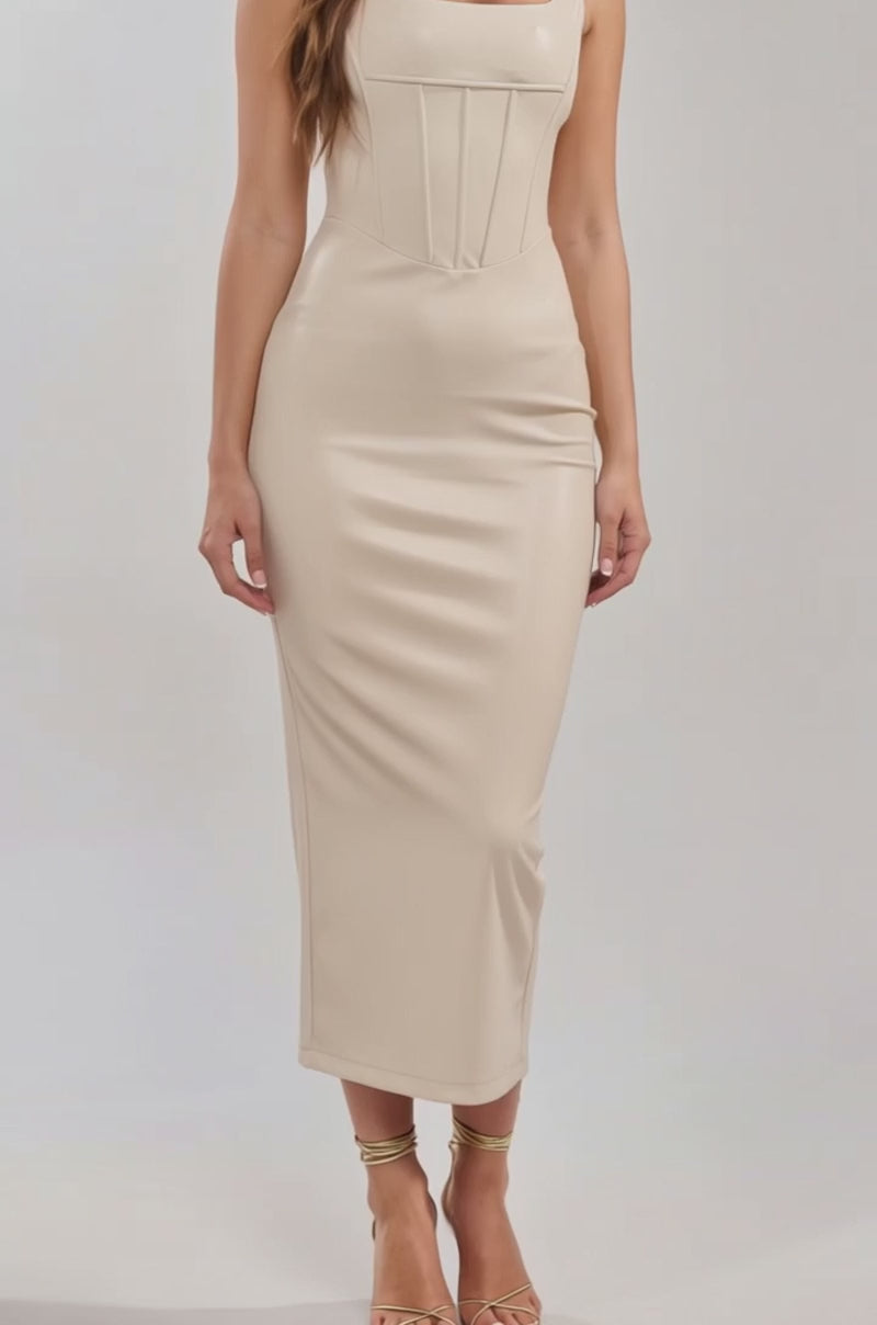 A video of a woman in the TONI Corset PU Maxi Dress in white, featuring a fitted silhouette, corseted bodice, square neckline, and seam detailing, paired with strappy high-heeled sandals.