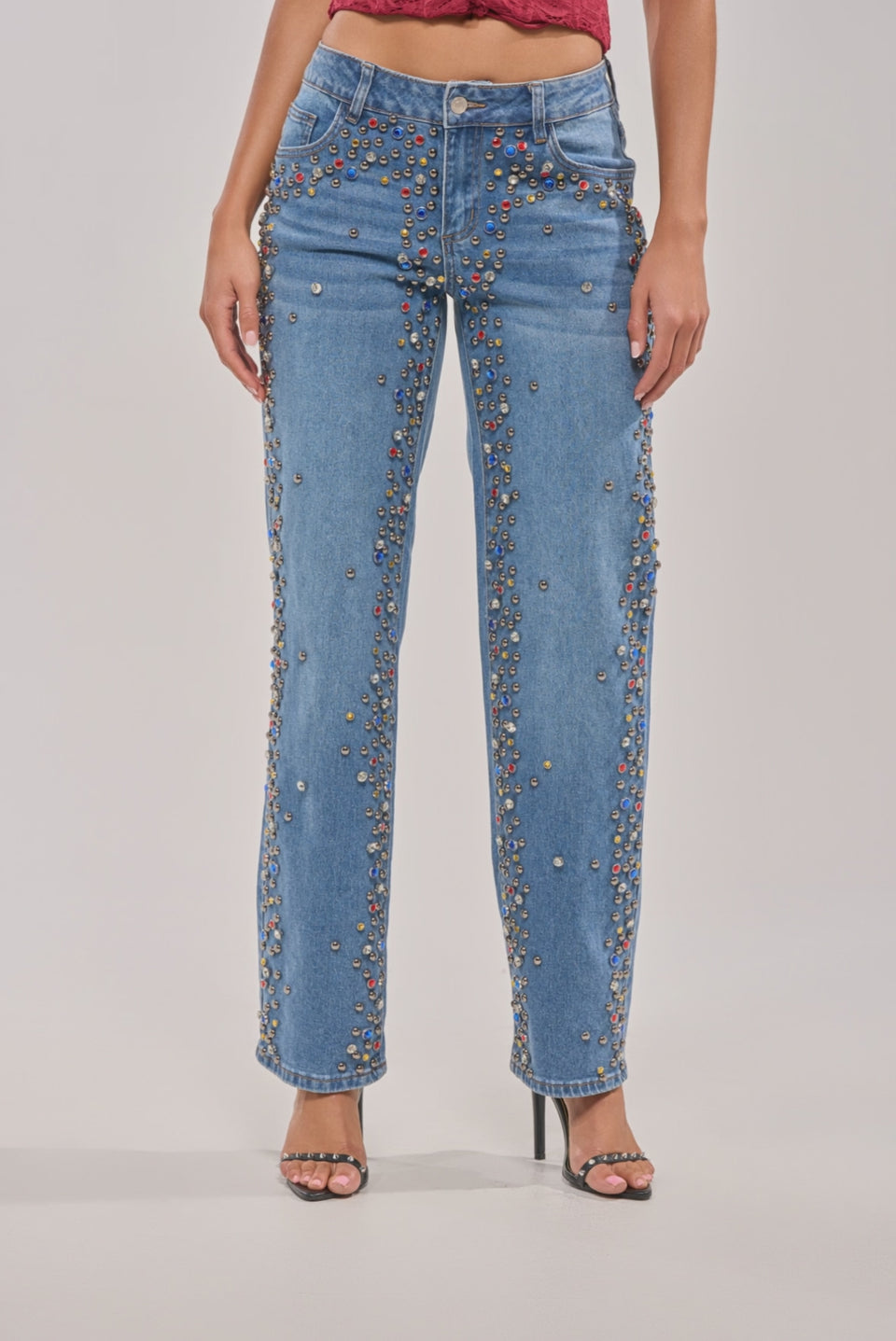 Video of woman modeling the JESSIE RHINESTONE DENIM jeans with a red sleeveless top and black high-heeled sandals 