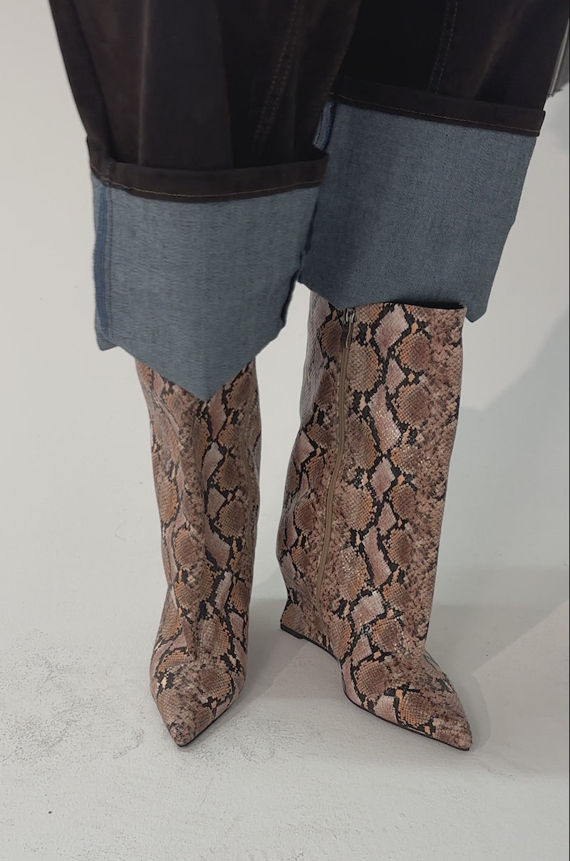 Video of woman modeling the AZALEA WANG VINCI SNAKE PU PRINT WEDGE BOOTIE with a beige and brown snakeskin pattern. The background is plain and light-colored.