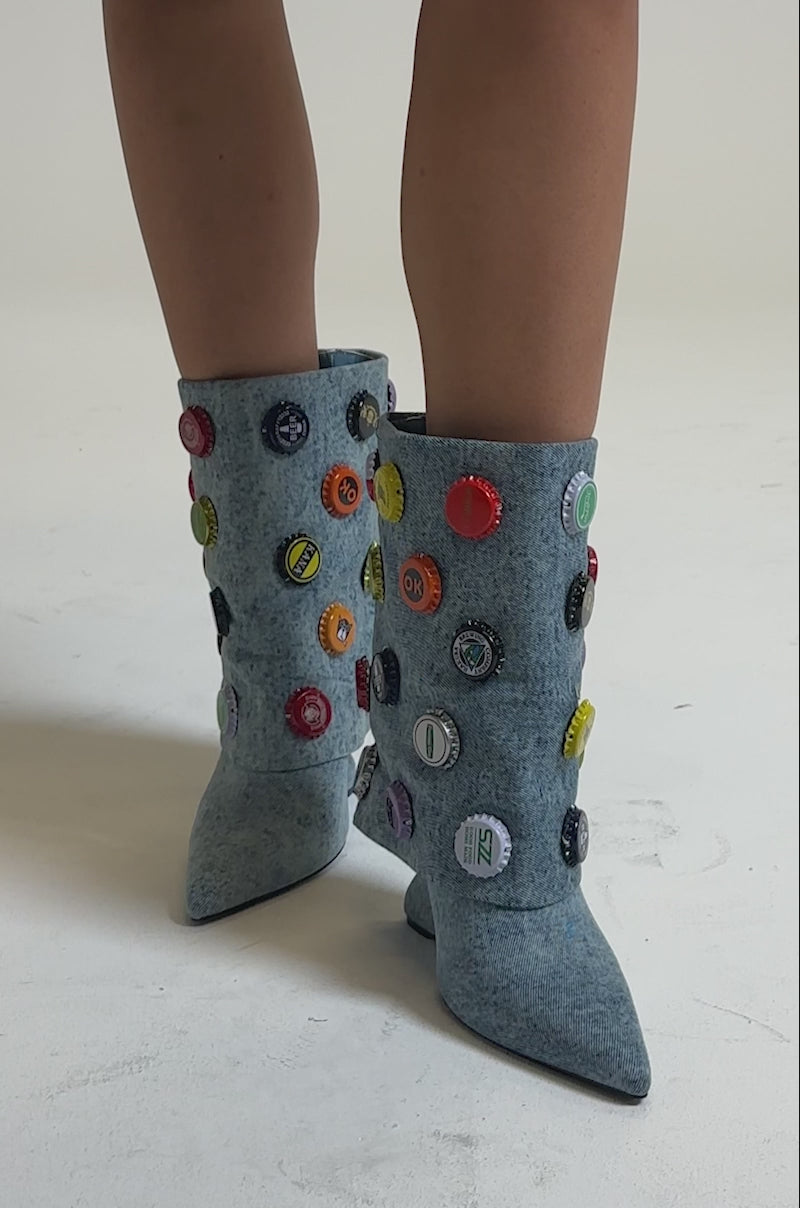 A video of a person wearing the AZALEA WANG EAVEN WEDGE EMBELLISHED DENIM BOOTIE—light blue booties with colorful patches and a slight wedge heel.