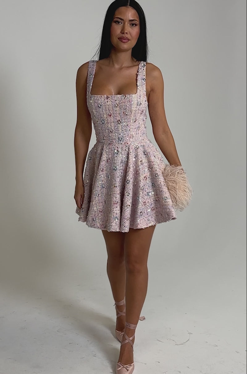 A video of a woman in the SWEET LIKE CANDY MINI DRESS, a pastel mini dress with a flared skirt, paired with pink ribbon ballet flats against a plain light background.