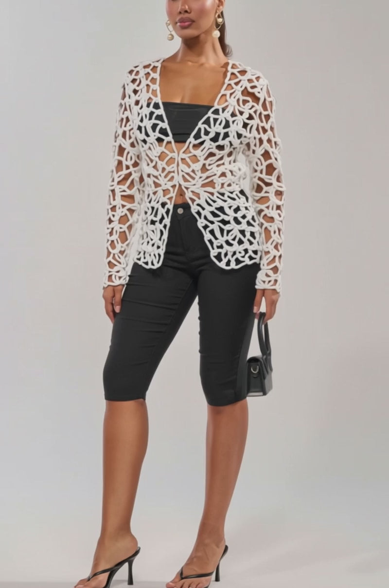 Video of woman modeling the LIKE YOU'VE NEVER SEEN CROCHET BLOUSE open over a black tube top and pants, accessorized with dangling earrings and a black handbag.