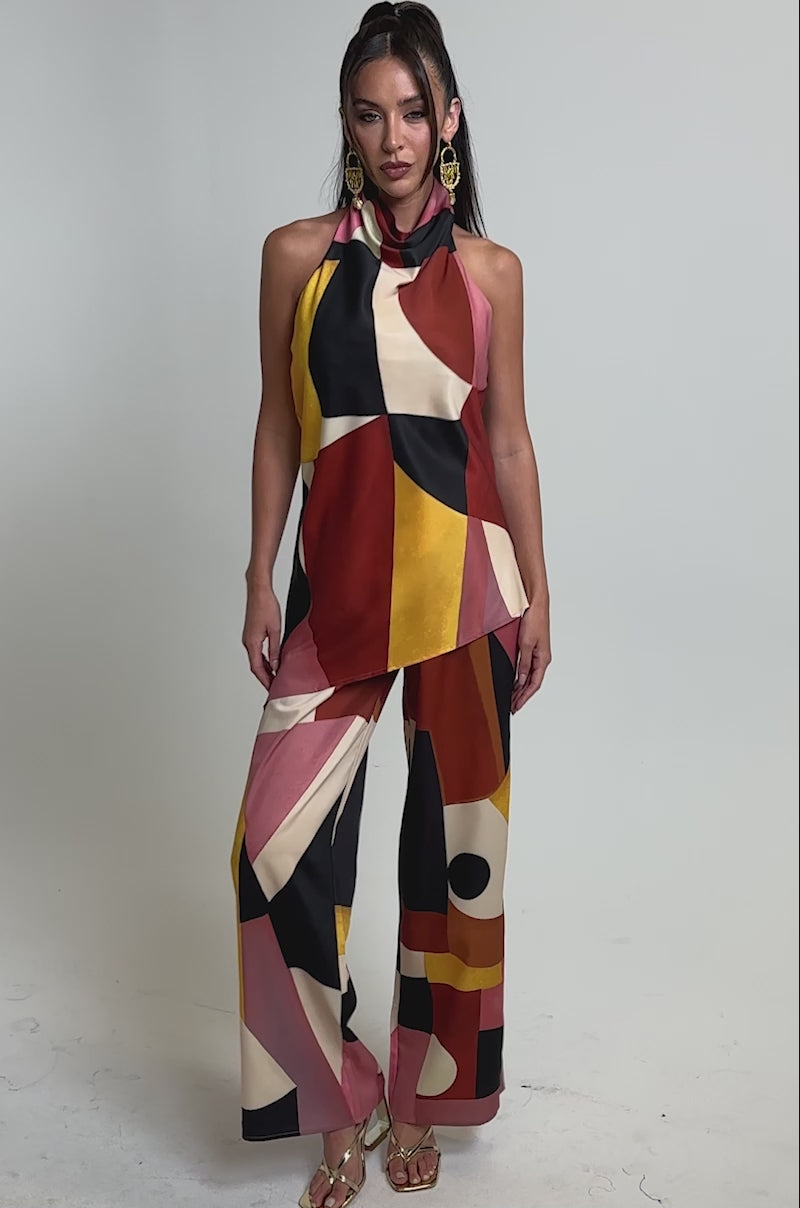 A video of a woman wearing the MIXED EMOTIONS BLOUSE with matching wide-leg pants, styled with statement earrings and gold heels.