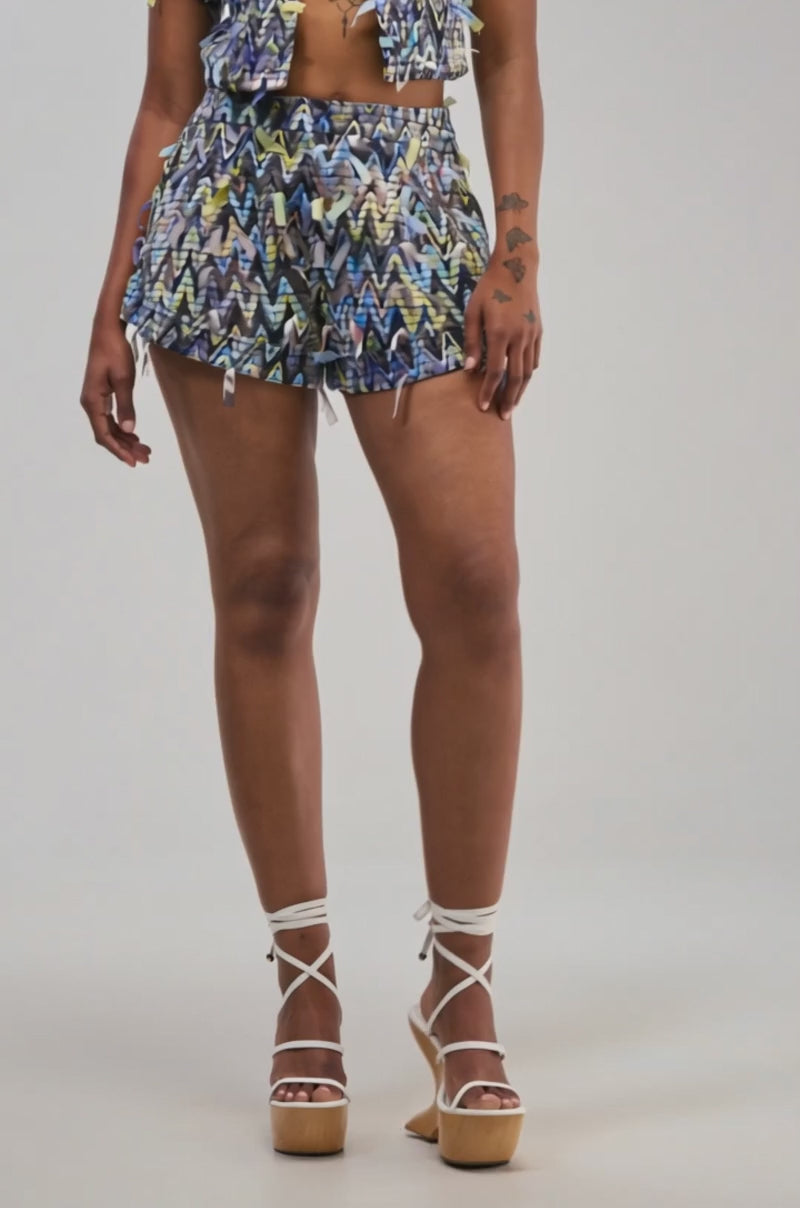 Video of a woman modeling the SWEET LIKE CANDY SHORT, a chevron print short adorned with fringe details.