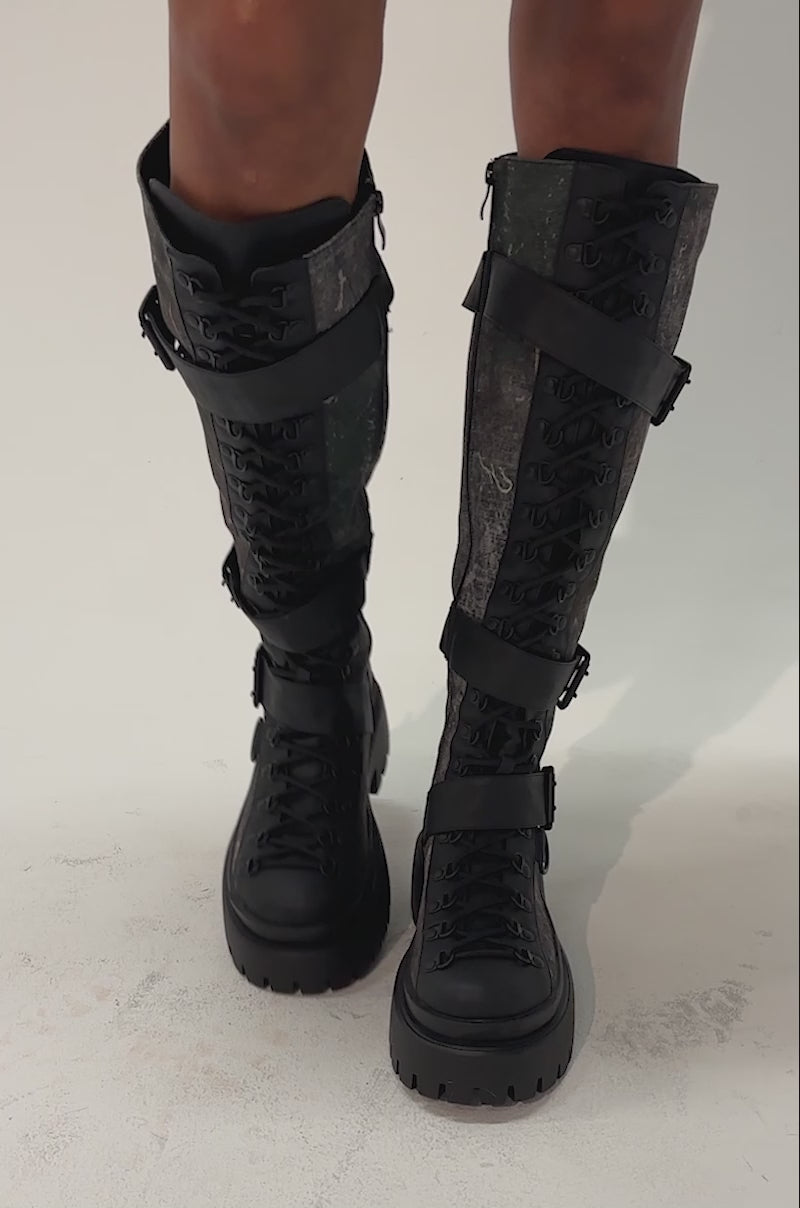 Video of a woman modeling the AZALEA WANG LYRA CAMO COMBAT BOOT, which features knee-high camouflage print, thick soles, and lace-up details.