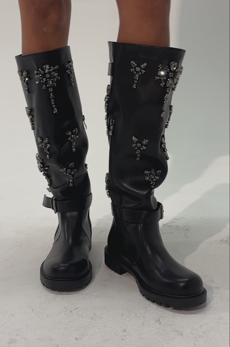 Video of a woman modeling the AZALEA WANG HANOVER BLACK EMBELLISHED FLAT BOOT—rhinestone knee-high boots with silver embellishments and buckles.