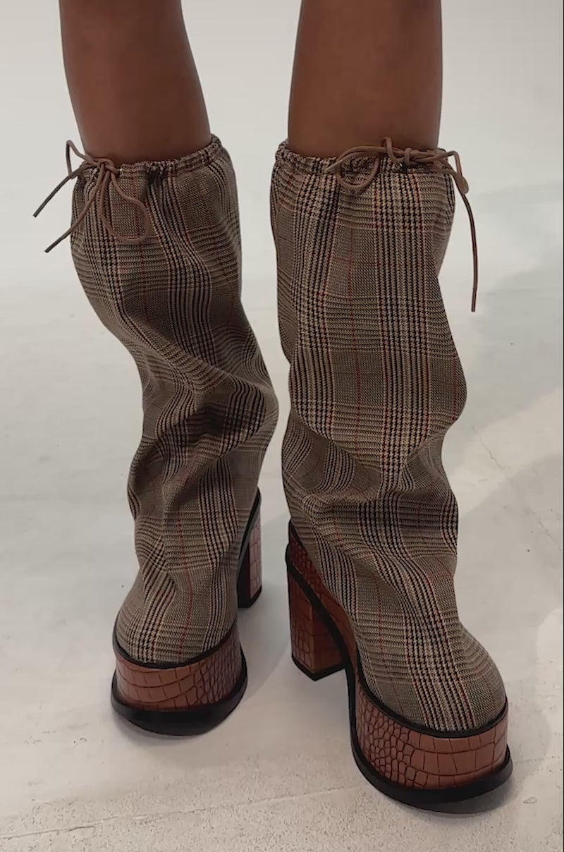 Video of woman modeling the AZALEA WANG LESLIE PLAID BLOCK PLATFORM SLOUCHY BOOT featuring slouchy brown plaid fabric with red accents, a drawstring top and a chunky crocodile-embossed brown platform heel
