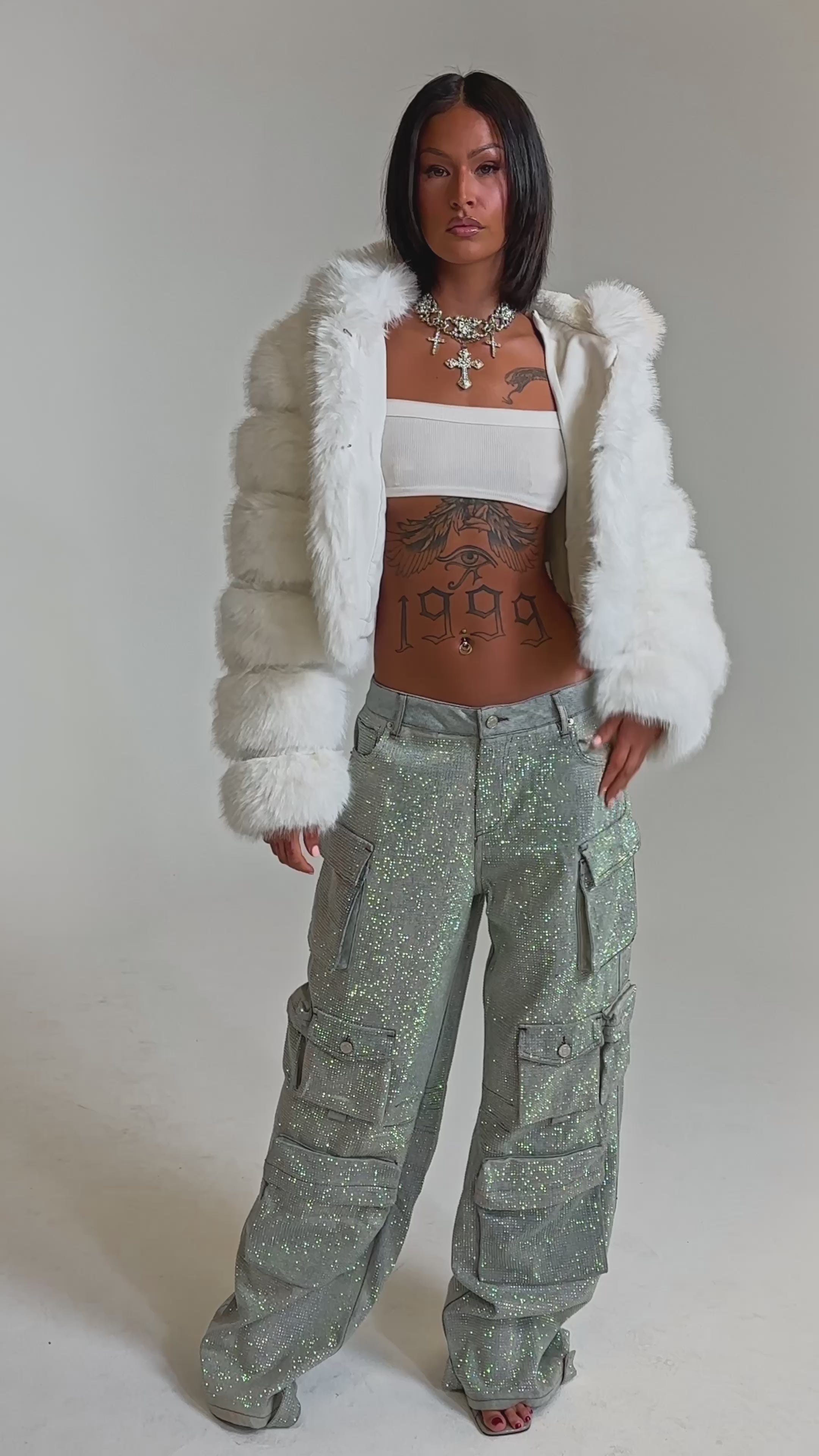 A video of a woman in the BLING BLING CARGO DENIM paired with a white faux fur jacket and bandeau top. 