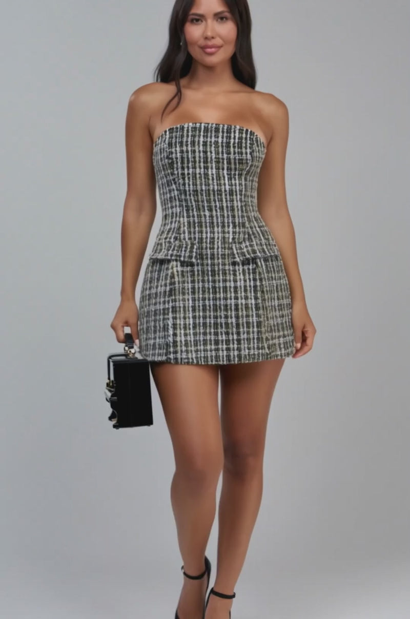 Video of a woman modeling the SERVING LOOKS STRAPLESS TWEED MINI DRESS, featuring a fitted, black-and-white plaid design and a short, strapless silhouette. 
