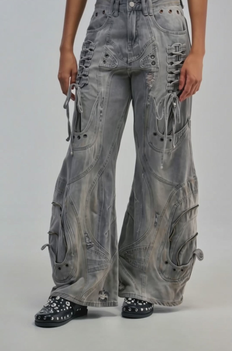Video of a woman modeling the COOL GIRL RELAXED DENIM—an oversized, wide-leg, grey washed cargo jean featuring lace-up details, distressed patches, and decorative stitching.