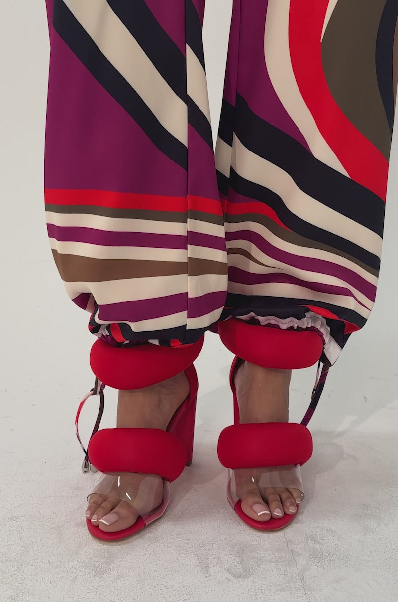 A video of a person wearing colorful, retro-patterned pants and the YANIX RED PUFF SLIP ON SANDAL.