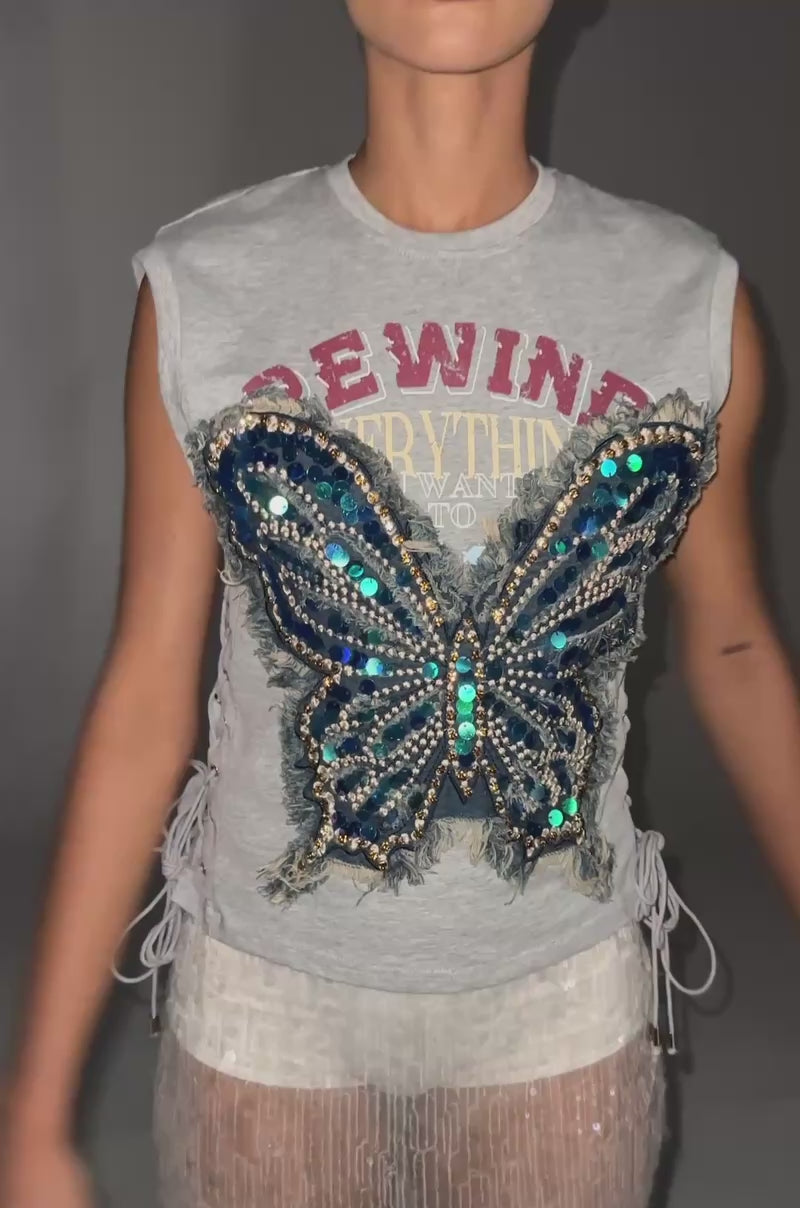 Video of woman modeling the REWIND EVERYTHING TEE IN LIGHT GREY, a sheer sequin skirt, and holding a tan bag standing against a plain background.