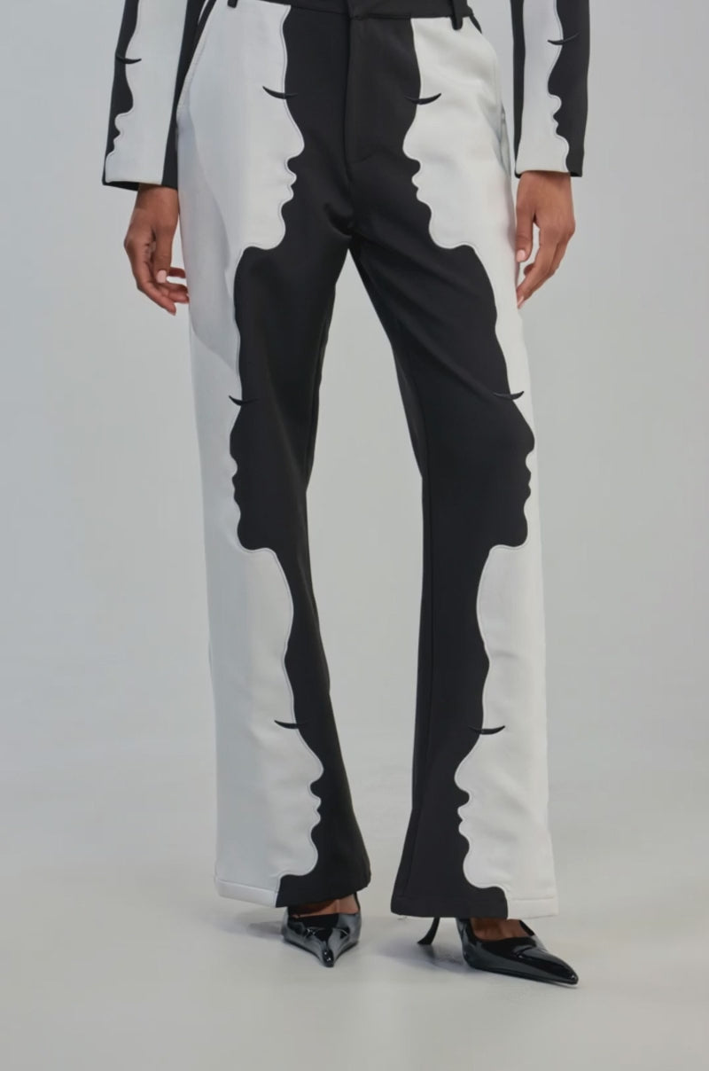 Video of a woman modeling the POV GRAPHIC TROUSER, which features high-rise wide-leg tailoring with abstract face profile designs along the legs.