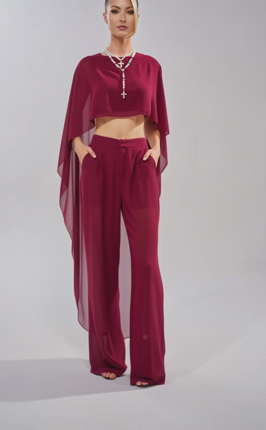 A video of a woman in the COOL GIRL TROUSER—a stylish, sheer burgundy high-rise chiffon pant—paired with a loose, flowing asymmetrical top and beaded necklace.