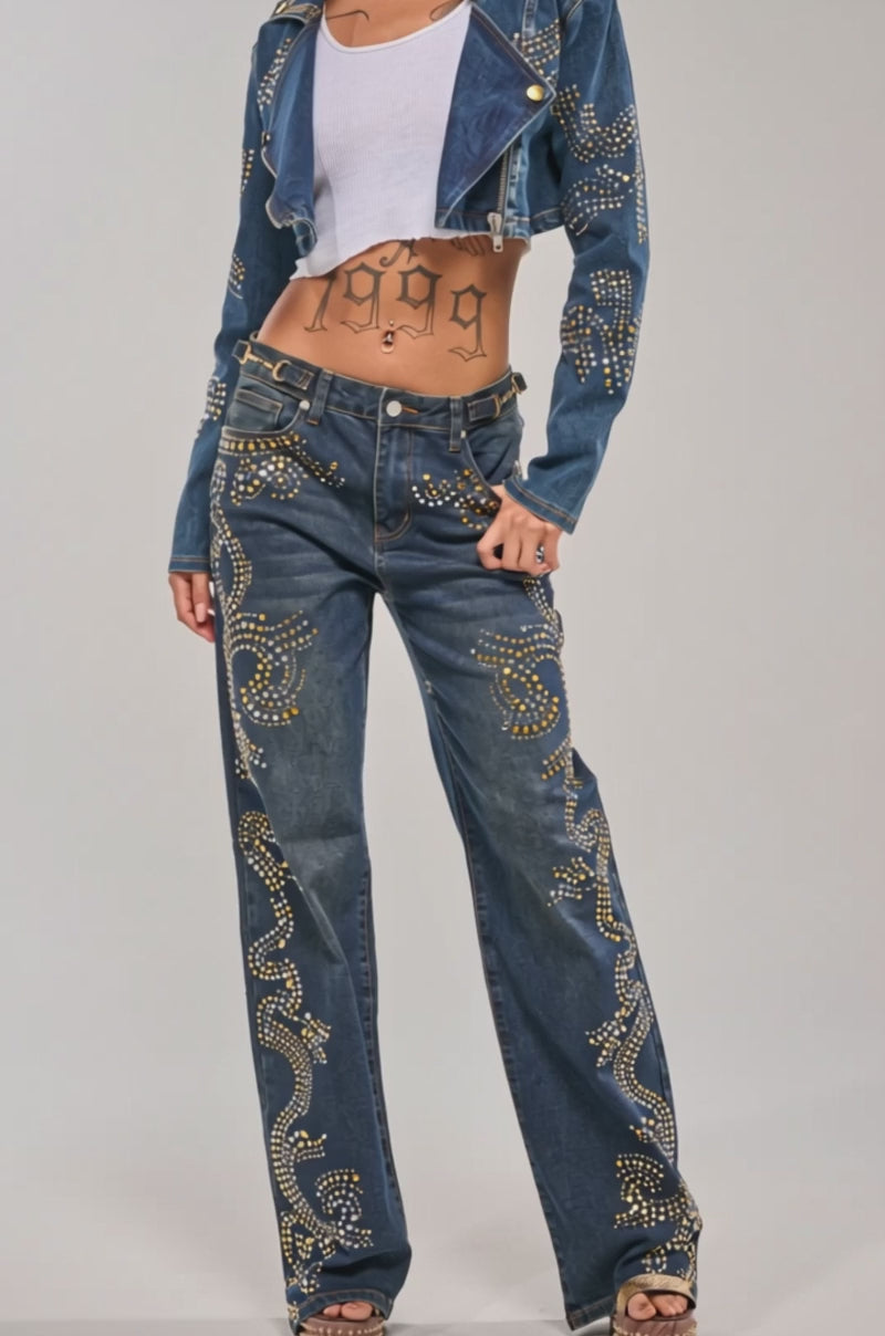 A video of a woman in the OFF TO THE RODEO CROPPED MOTO, a studded denim moto jacket with matching jeans featuring swirling gold studs. 