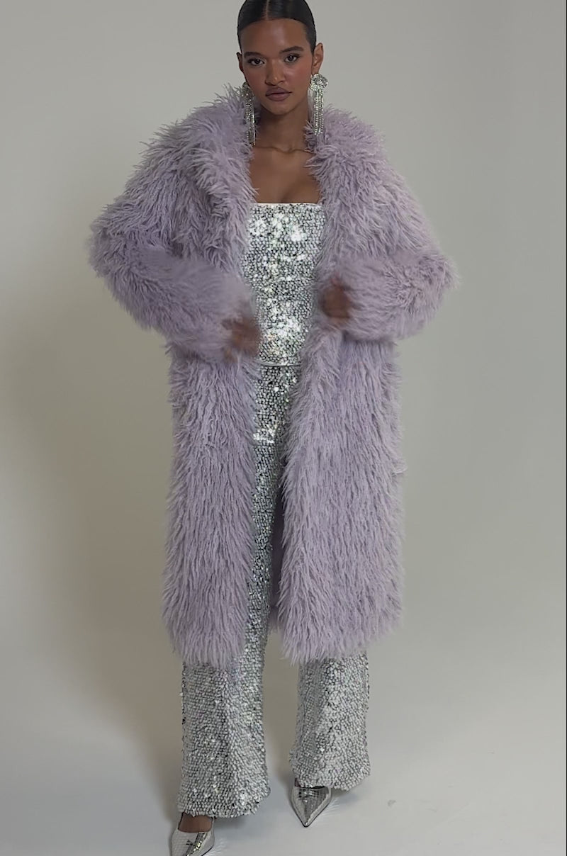 Video of woman modeling the VIOLET SKIES FAUX FUR COAT from AKIRA Label, worn over a sparkling silver outfit.