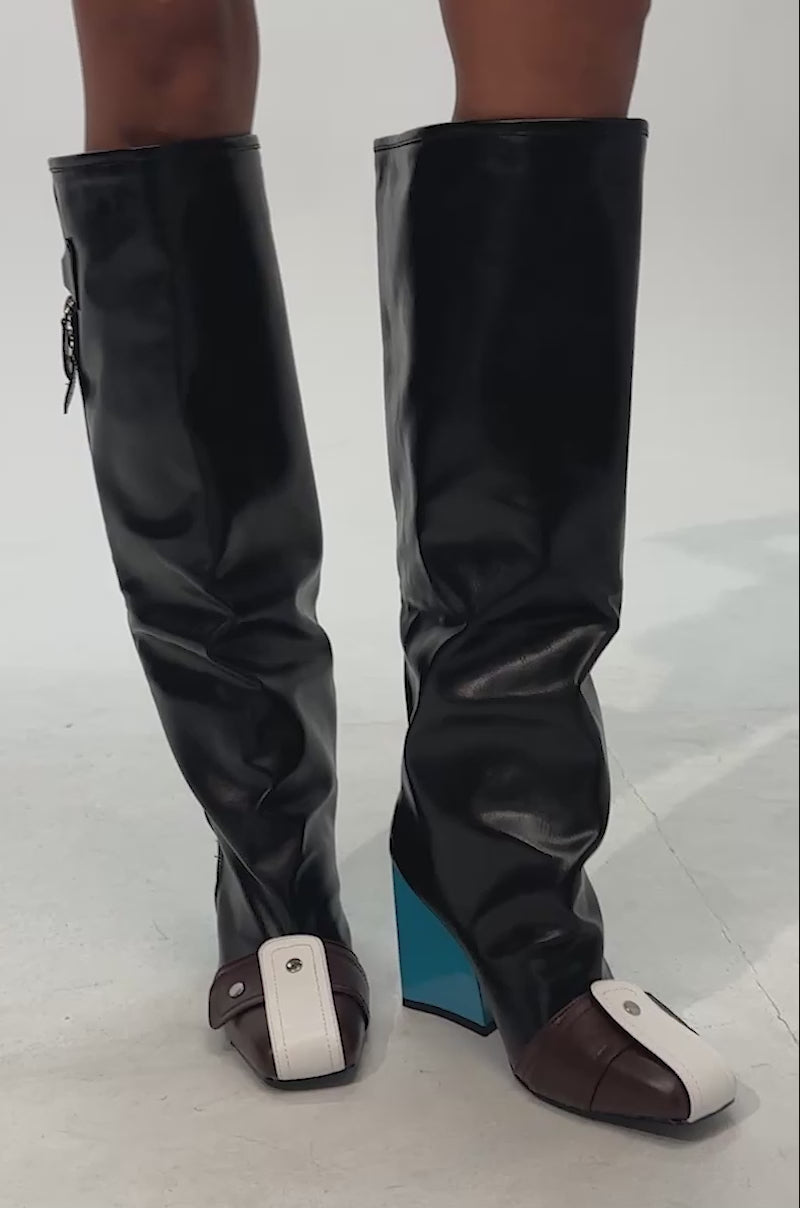 Video of woman modeling the AZALEA WANG AXTON BLACK MULTI COLOR BLOCKED BLOCK BOOT, featuring black knee-high shafts, brown pointed toes, and shiny blue color-blocked block heels
