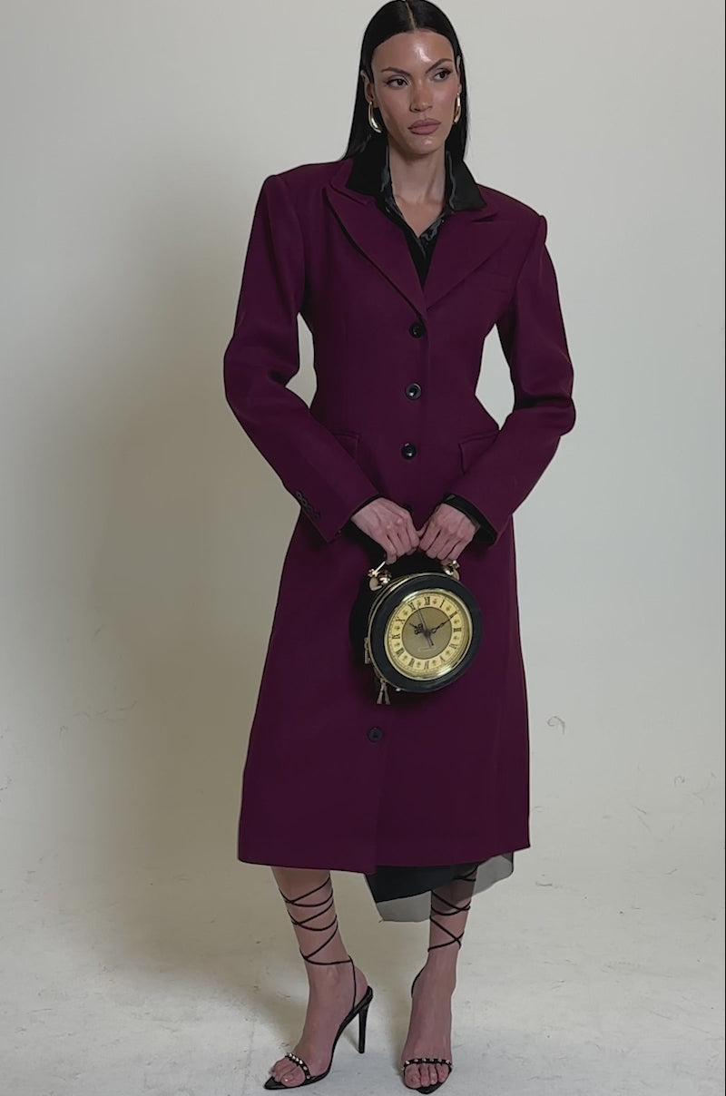 A video of a woman wearing the SCARLETT LUXE TRENCH IN PURPLE, featuring a longline silhouette and black lapels. 