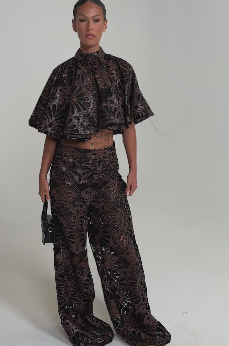 A video of a woman in the LENA LACE AND PU BLOUSE with matching wide-leg pants, featuring intricate lace details.