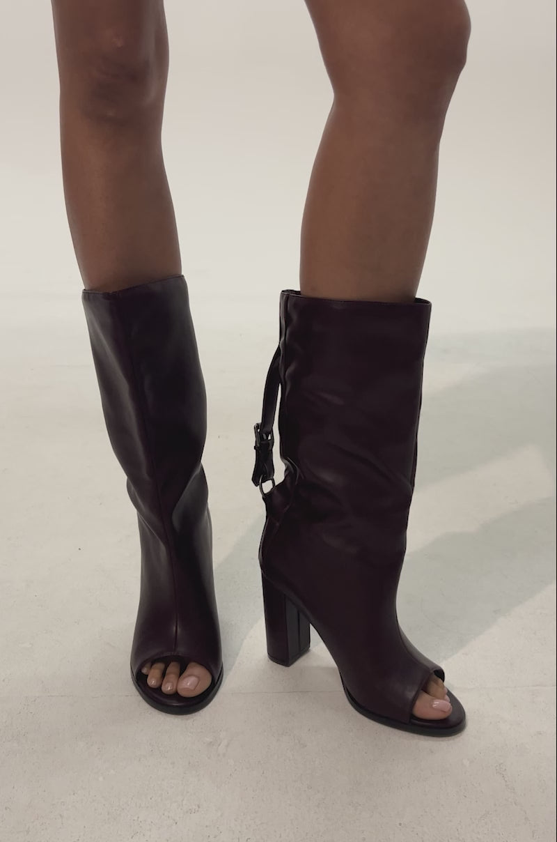 Video of woman modeling the AKIRA GOLD REMIX MAHOGANY OPEN TOE BLOCK BOOTIE— mahogany booties with open toes, block heels, side buckles, and a stylish leather or faux leather appearance.