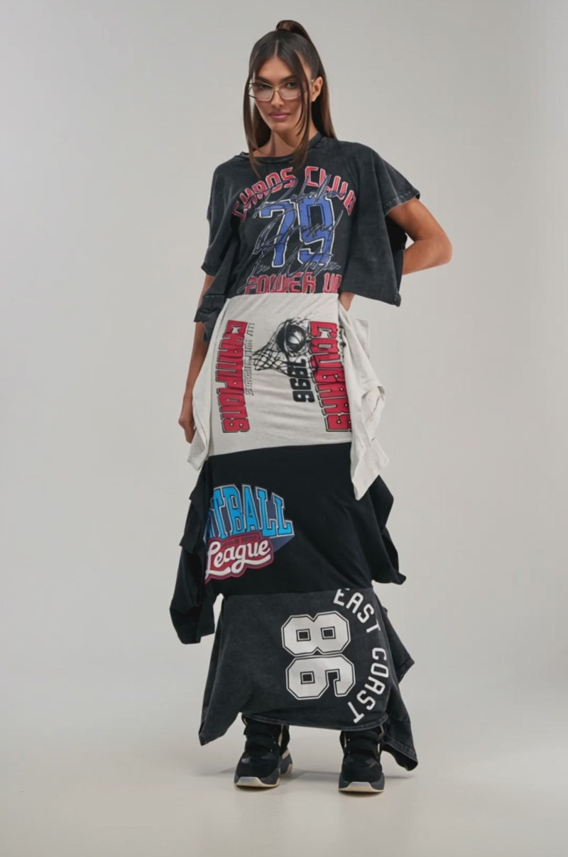 A video of a woman wearing the YOUR BIGGEST FAN GRAPHIC TEE MAXI DRESS in black, gray, and blue with black sneakers, standing against a plain light background.