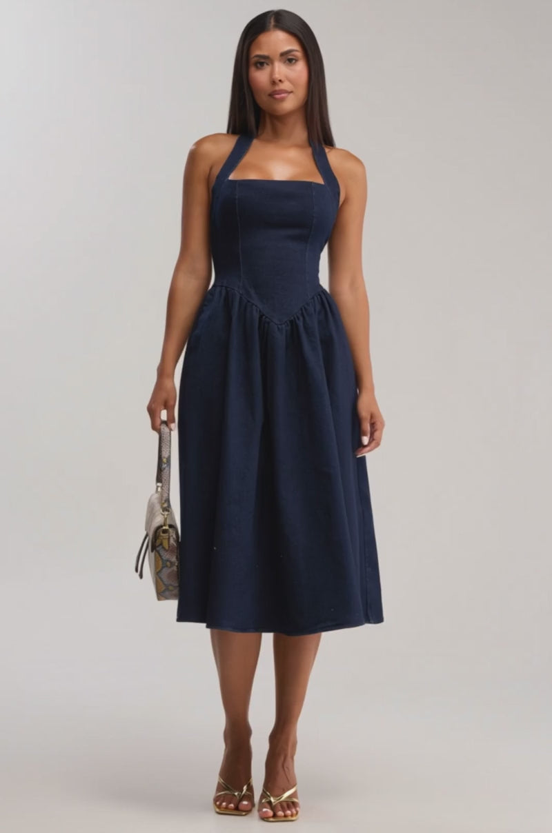 A video of a woman wearing the MISS INDEPENDENT DENIM HALTER MIDI DRESS—a sleeveless, dark wash midi with a square neckline.