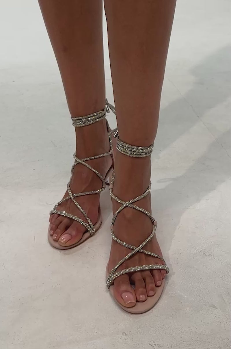 Video of woman modeling the AKIRA ARTEMISA NUDE RHINESTONE LACE UP SANDAL with clear block heels on a white background.