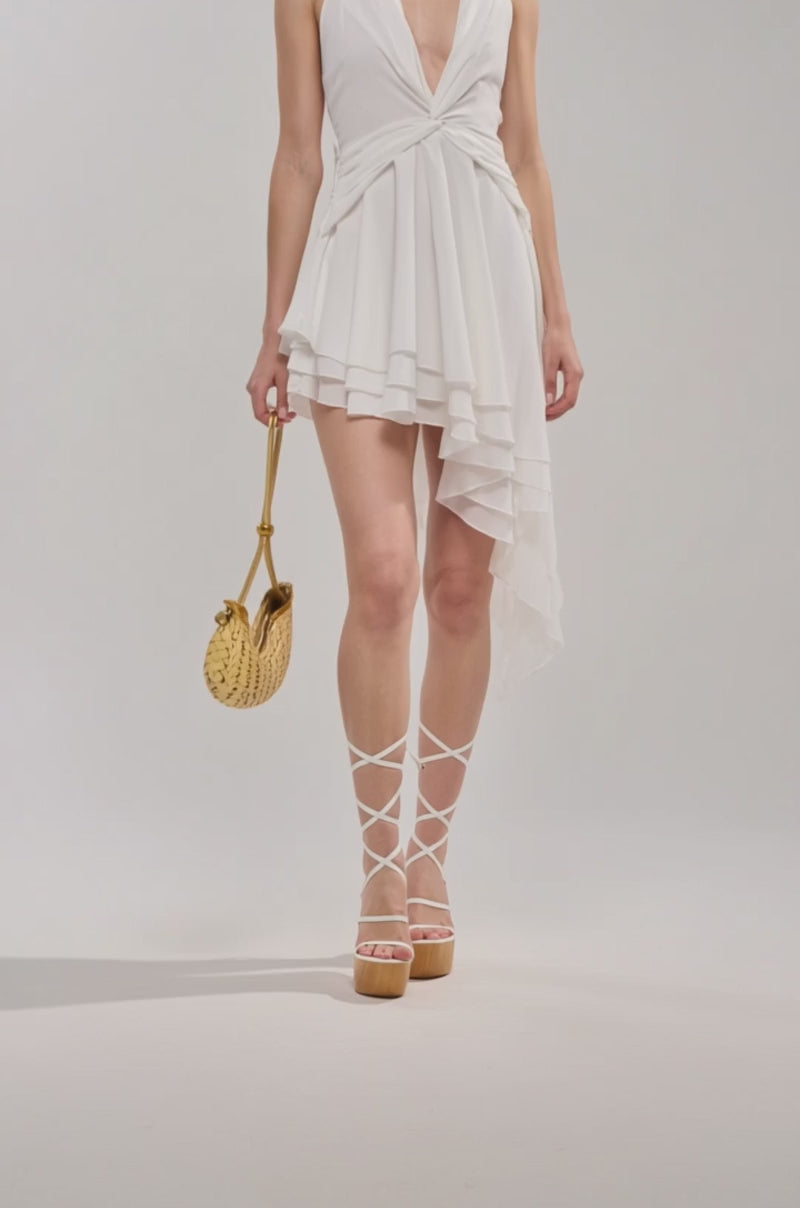 Video of woman modeling the SUMMER DAYS MINI DRESS IN IVORY, styled with strappy white heels and a small woven gold handbag, standing confidently against a plain light background.