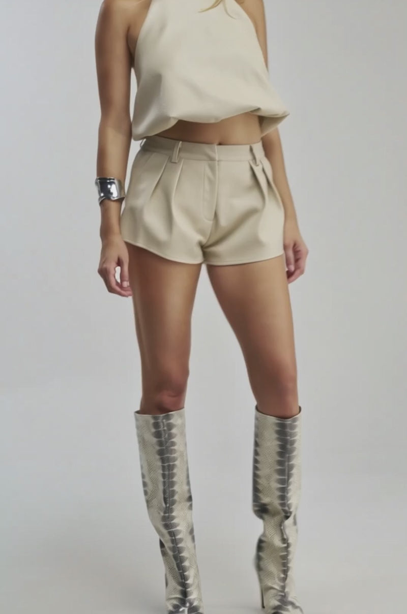 Video of a woman modeling the UBAE LEATHER TOP—a cream faux leather sleeveless halter.
