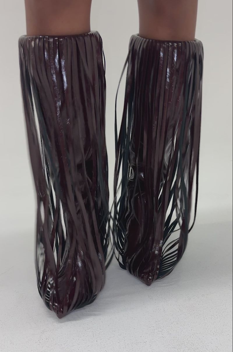 Video of woman modeling the AZALEA WANG XANTARA FRINGE BURGUNDY STILETTO BOOT features a high heel and long, narrow vertical fringe strips in burgundy, giving the boot a textured, layered look.
