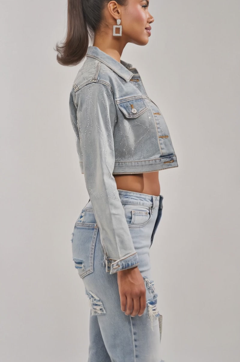 A video of a woman in the DAZED RHINESTONE DENIM JACKET, lace bralette, high-waisted ripped jeans, and heeled sandals.