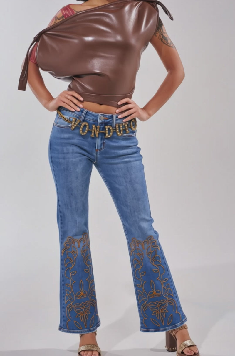 Video of woman modeling the WEEKEND VIBES FAUX LEATHER BLOUSE IN BROWN, paired with blue jeans and a gold-buckled belt.